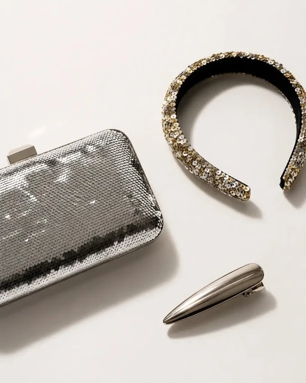 Accessoires paillettes femme : pochette à sequins, serre-tête et barrette sur fond sombre